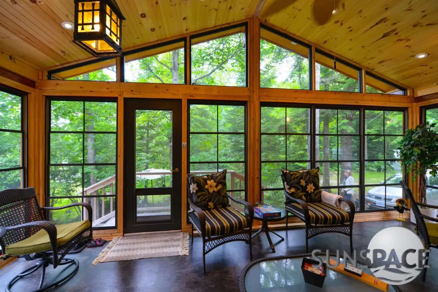 Sunroom with chairs, glass door, and large windows