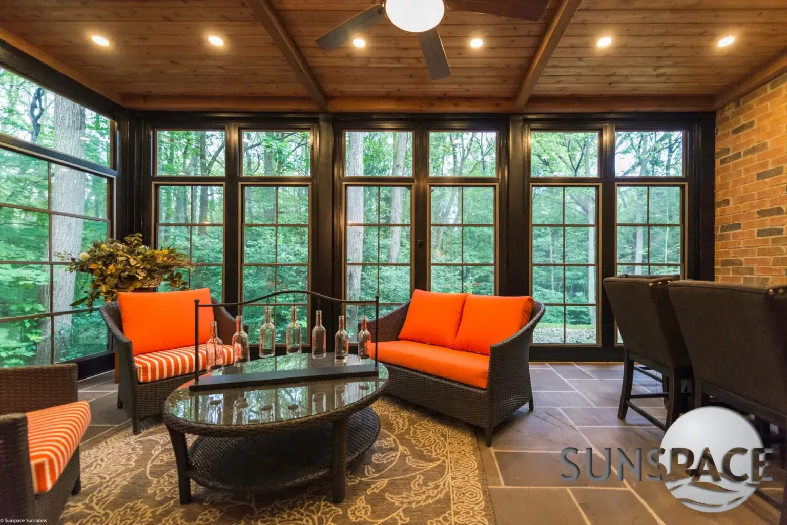 Sunroom featuring orange wicker furniture and a ceiling fan, creating a cozy and inviting atmosphere.
