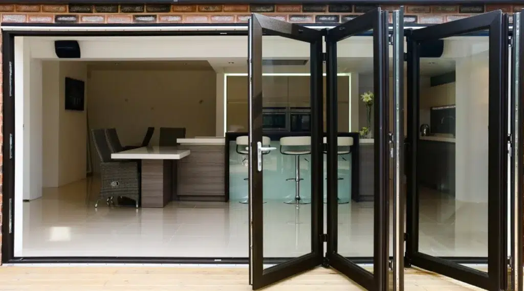 Large sliding glass door with WeatherMaster™ Plus Bi-Fold system opening to modern kitchen and dining area.